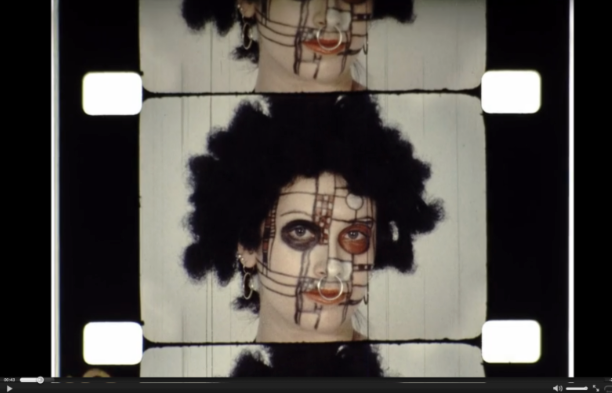still from a film of a person with facepaint and black wig