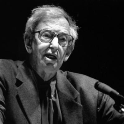 Black and white photo of a man speaking into a microphone.